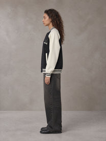 Model wearing the SM Varsity Jacket in Midnight Black, side profile.
