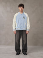 Model wearing the SM Varsity Jacket in Powder Blue, front view.