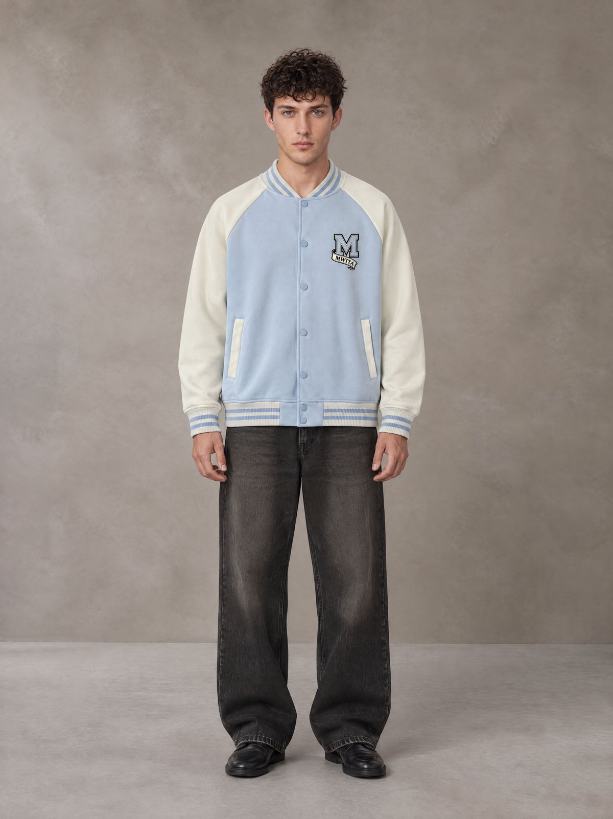 Model wearing the SM Varsity Jacket in Powder Blue, front view.