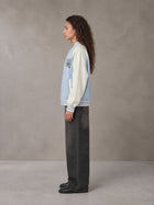 Model wearing the SM Varsity Jacket in Powder Blue, side profile.