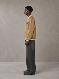 Model wearing the SM Varsity Jacket in Camel Tan, side profile.