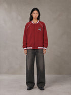 Model wearing the SM Varsity Jacket in Carmine, front view.