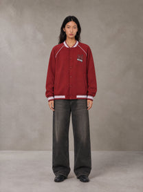 Model wearing the SM Varsity Jacket in Carmine, front view.