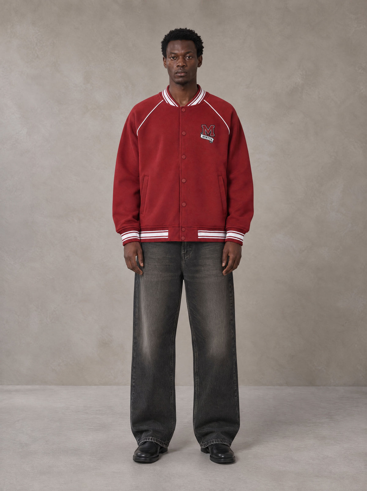 Model wearing the SM Varsity Jacket in Carmine, front view.