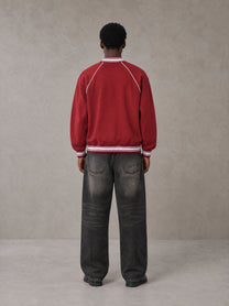 Model wearing the SM Varsity Jacket in Carmine, rear view.