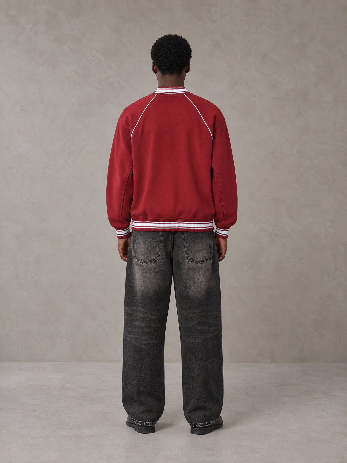 Model wearing the SM Varsity Jacket in Carmine, rear view.