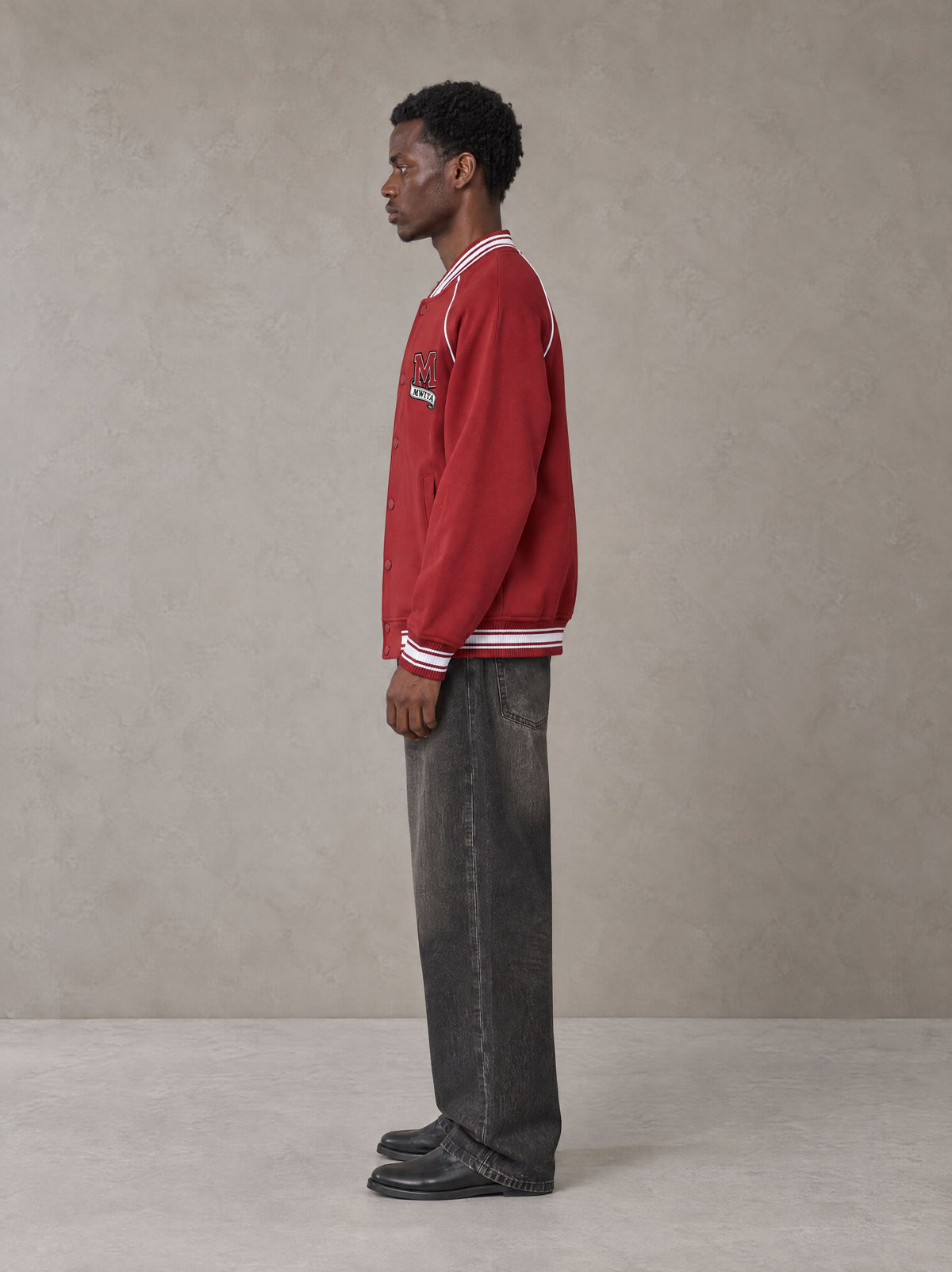 Model wearing the SM Varsity Jacket in Carmine, side profile.