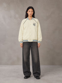 Model wearing the SM Varsity Jacket in Classic Cream, front view.