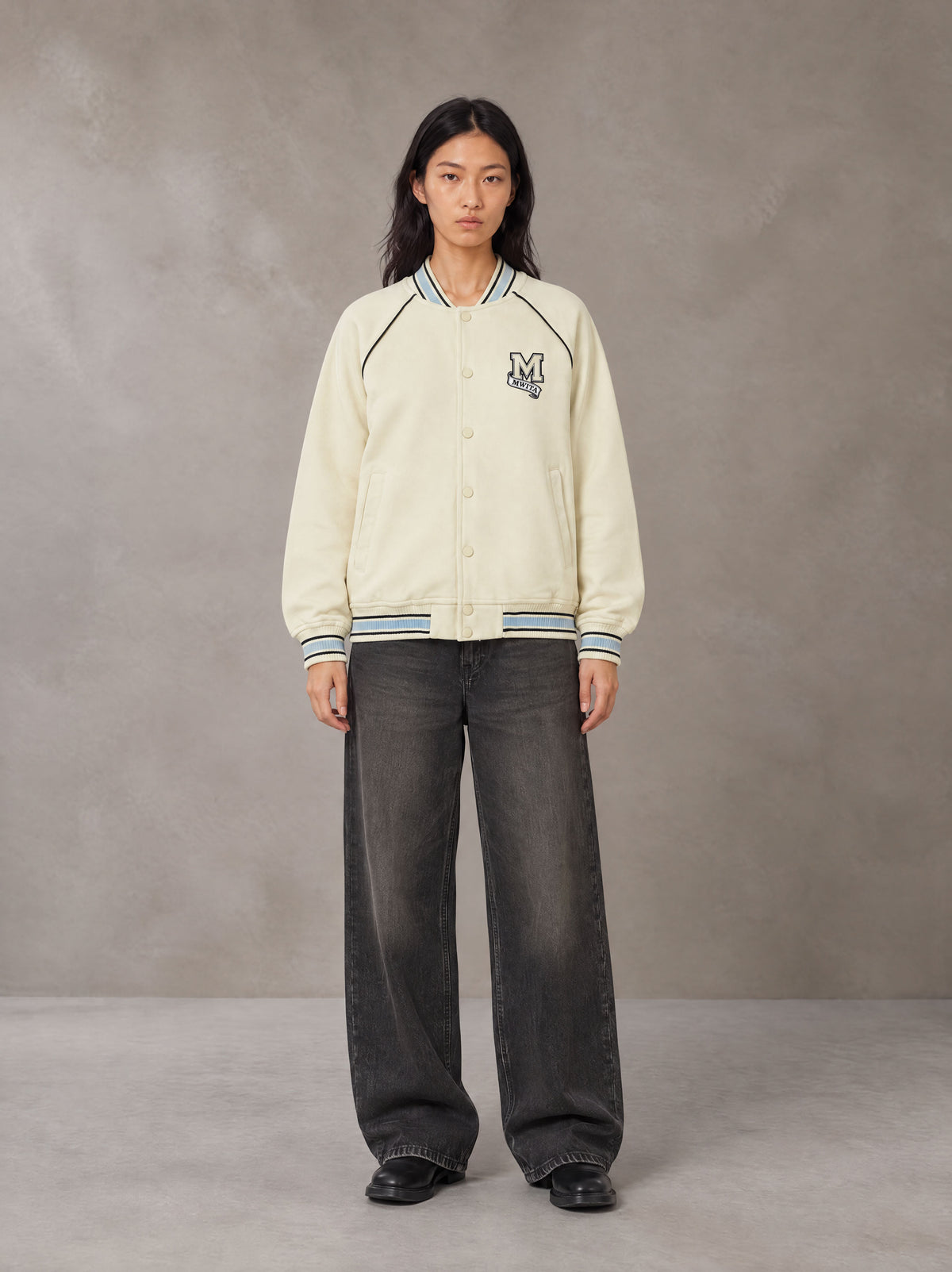 Model wearing the SM Varsity Jacket in Classic Cream, front view.