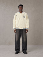 Model wearing the SM Varsity Jacket in Classic Cream, front view.
