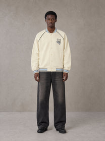 Model wearing the SM Varsity Jacket in Classic Cream, front view.