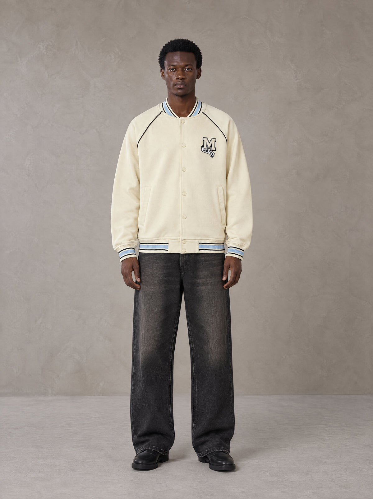 Model wearing the SM Varsity Jacket in Classic Cream, front view.