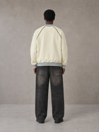Model wearing the SM Varsity Jacket in Classic Cream, rear view.