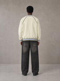 Model wearing the SM Varsity Jacket in Classic Cream, rear view.