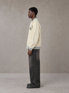 Model wearing the SM Varsity Jacket in Classic Cream, side profile.