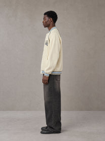 Model wearing the SM Varsity Jacket in Classic Cream, side profile.