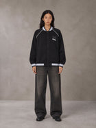 Model wearing the SM Varsity Jacket in Midnight Black, front view.