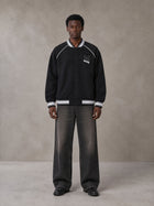 Model wearing the SM Varsity Jacket in Midnight Black, front view.