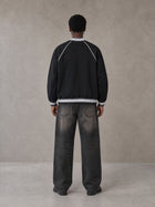 Model wearing the SM Varsity Jacket in Midnight Black, rear view.