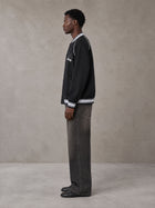 Model wearing the SM Varsity Jacket in Midnight Black, side profile.