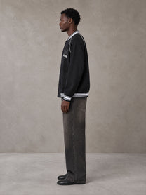 Model wearing the SM Varsity Jacket in Midnight Black, side profile.