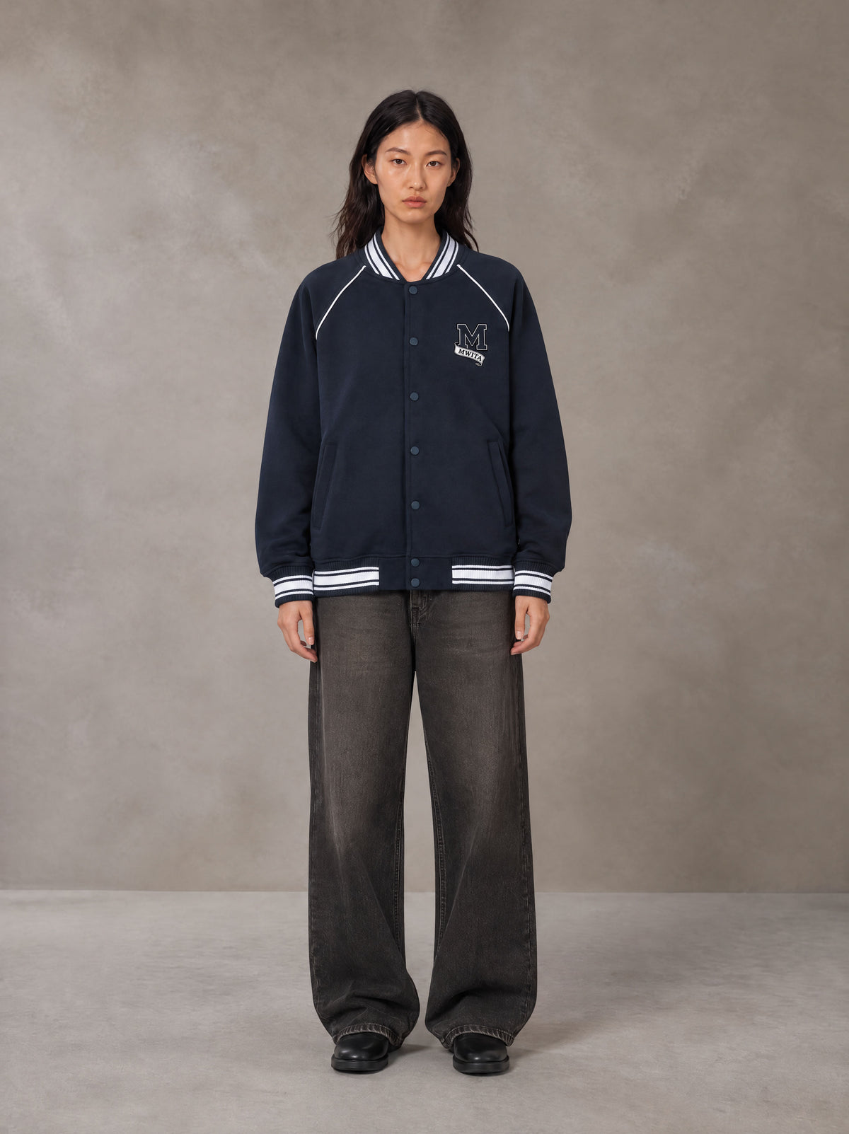 Model wearing the SM Varsity Jacket in Oxford Navy, front view.