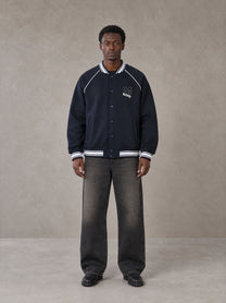 Model wearing the SM Varsity Jacket in Oxford Navy, front view.