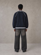 Model wearing the SM Varsity Jacket in Oxford Navy, rear view.