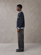 Model wearing the SM Varsity Jacket in Oxford Navy, side profile.