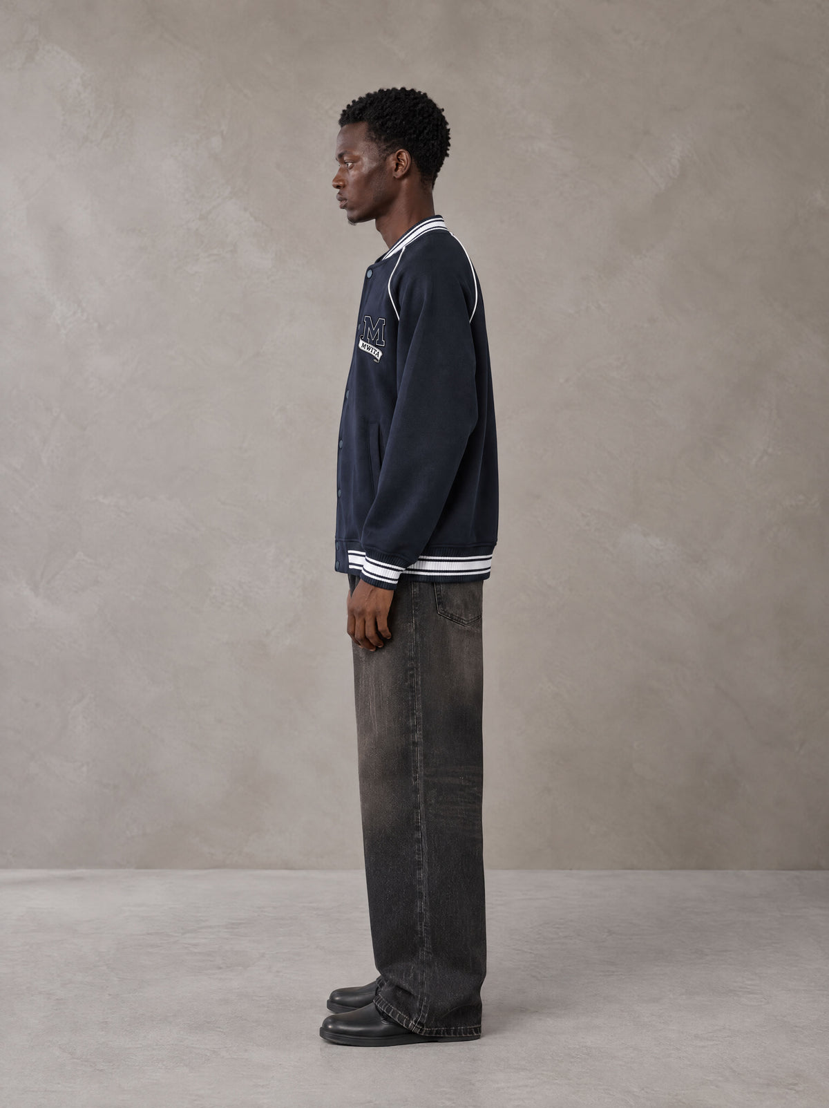 Model wearing the SM Varsity Jacket in Oxford Navy, side profile.