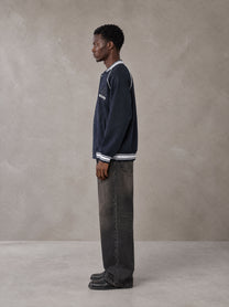 Model wearing the SM Varsity Jacket in Oxford Navy, side profile.