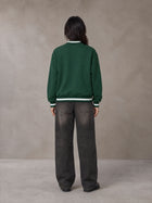 Model wearing the SM Varsity Zip Jacket in Alpine Green, rear view.