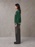 Model wearing the SM Varsity Zip Jacket in Alpine Green, side profile.