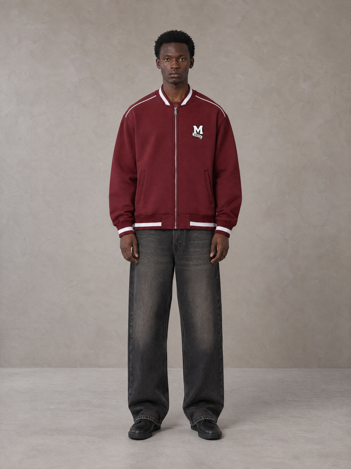 Model wearing the SM Varsity Zip Jacket in Burgundy, front view.