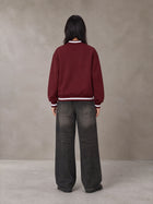Model wearing the SM Varsity Zip Jacket in Burgundy, rear view.