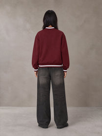Model wearing the SM Varsity Zip Jacket in Burgundy, rear view.