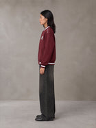 Model wearing the SM Varsity Zip Jacket in Burgundy, side profile.