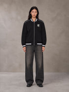 Model wearing the SM Varsity Zip Jacket in Midnight Black, front view.