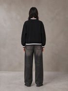 Model wearing the SM Varsity Zip Jacket in Midnight Black, rear view.