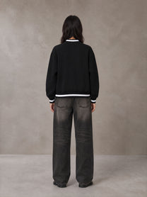 Model wearing the SM Varsity Zip Jacket in Midnight Black, rear view.