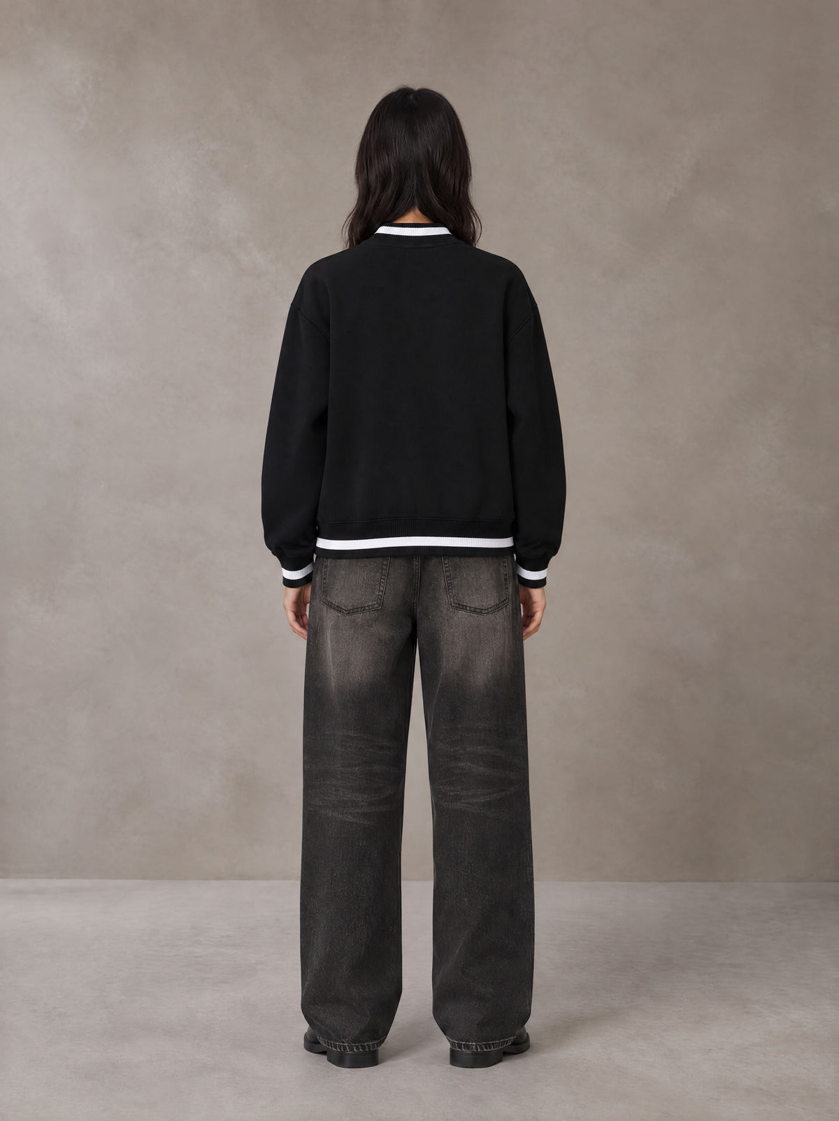 Model wearing the SM Varsity Zip Jacket in Midnight Black, rear view.