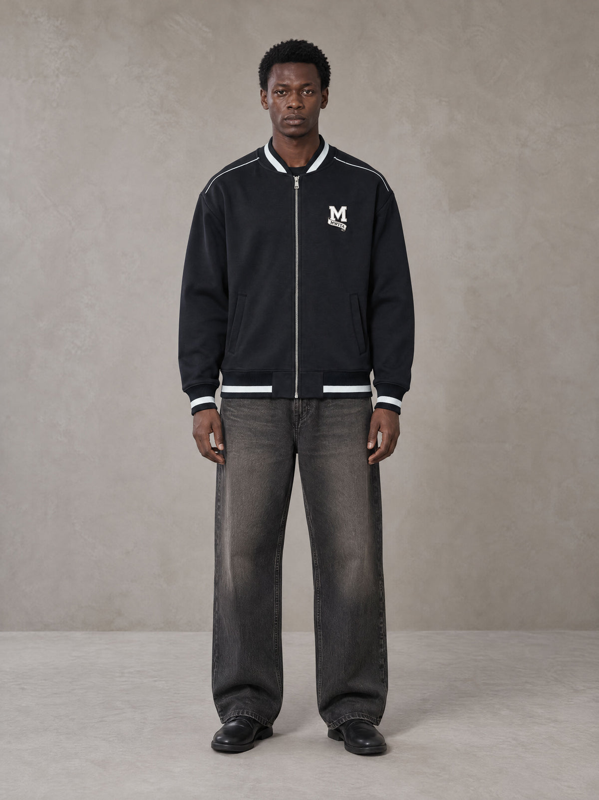 Model wearing the SM Varsity Zip Jacket in Oxford Navy, front view.