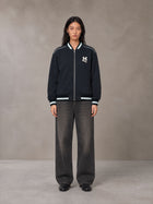 Model wearing the SM Varsity Zip Jacket in Oxford Navy, front view.