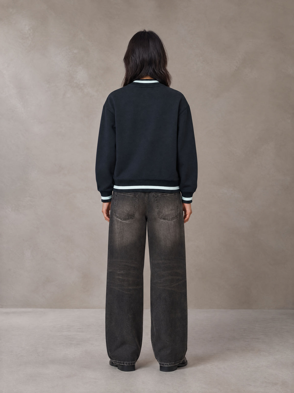 Model wearing the SM Varsity Zip Jacket in Oxford Navy, rear view.