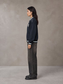 Model wearing the SM Varsity Zip Jacket in Oxford Navy, side profile.