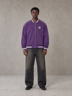 Model wearing the SM Varsity Zip Jacket in Rich Violet, front view.