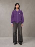 Model wearing the SM Varsity Zip Jacket in Rich Violet, front view.