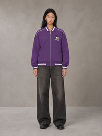 Model wearing the SM Varsity Zip Jacket in Rich Violet, front view.
