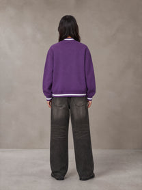 Model wearing the SM Varsity Zip Jacket in Rich Violet, rear view.