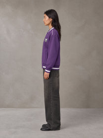 Model wearing the SM Varsity Zip Jacket in Rich Violet, side profile.
